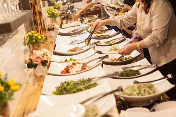 Ludzie serwujący sobie jedzenie w formie bufetu jako catering na spotkania biznesowe.