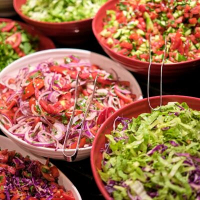 Różnorodne sałatki w misach na stole cateringowym.